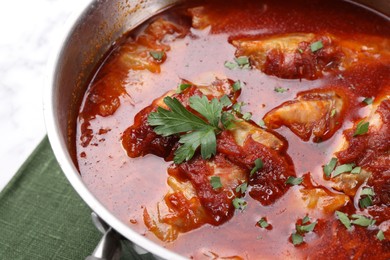 Photo of Delicious stuffed cabbage rolls cooked with homemade tomato sauce in pot on table, closeup