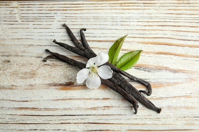 Photo of Aromatic vanilla sticks and flower on wooden background
