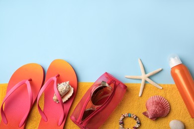 Flat lay composition with sunscreen and beach accessories on light blue background. Space for text