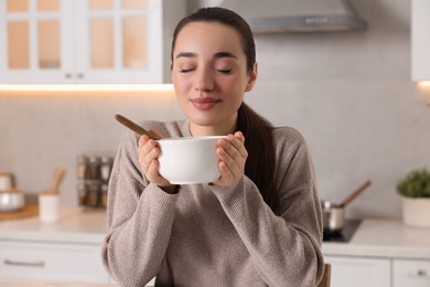 Photo of Woman with bowl of tasty soup in kitchen