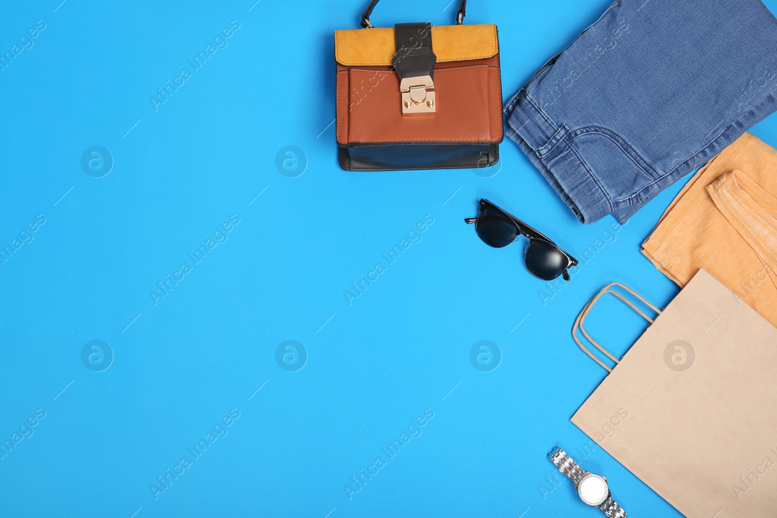 Photo of Stylish flat lay composition with shopping bag and clothing on color background