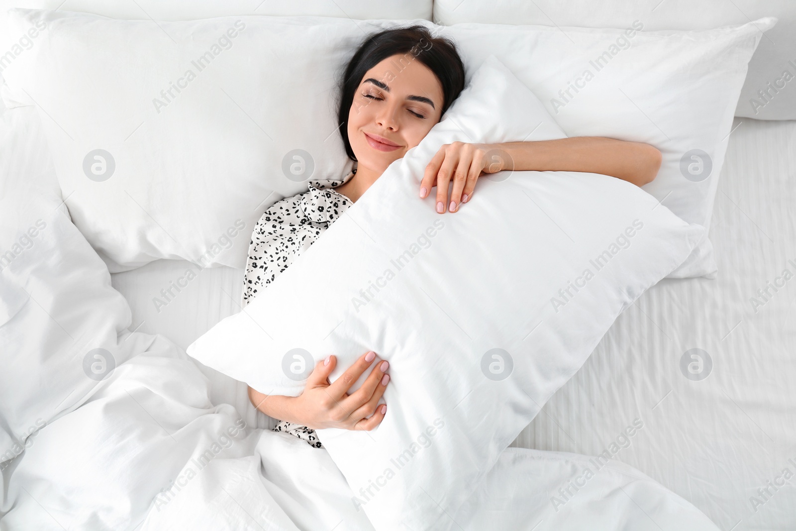 Photo of Young woman with pillow in bed, top view. Lazy morning