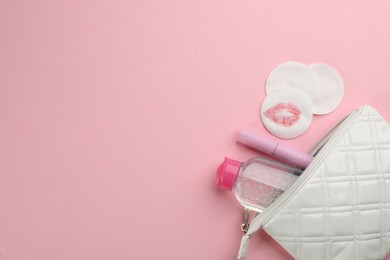 Photo of Clean and dirty cotton pads, cleansing water with mascara in bag on light pink background, flat lay. Space for text