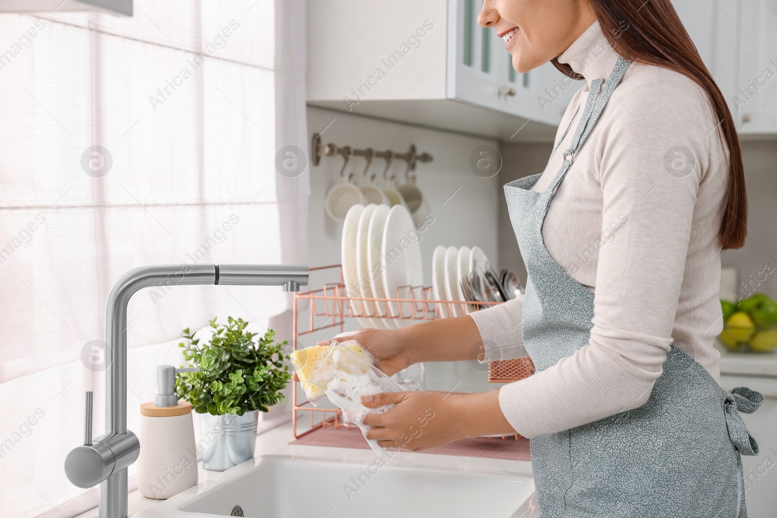 Photo of Woman washing glass at sink in kitchen, closeup