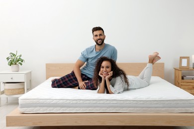 Happy couple on bed with comfortable mattress at home