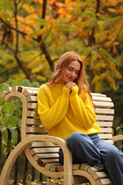 Beautiful woman sitting on bench in autumn park