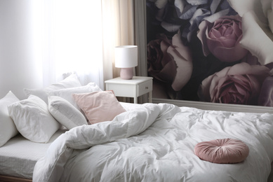 Comfortable bed near wall with floral wallpaper. Stylish room interior