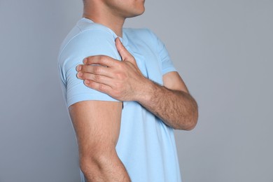 Photo of Man suffering from shoulder pain on grey background, closeup