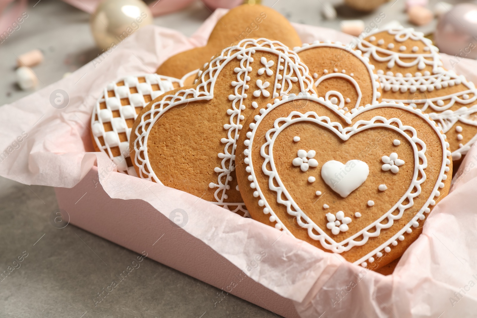 Photo of Tasty heart shaped gingerbread cookies in box on grey table, closeup