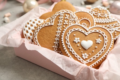 Tasty heart shaped gingerbread cookies in box on grey table, closeup