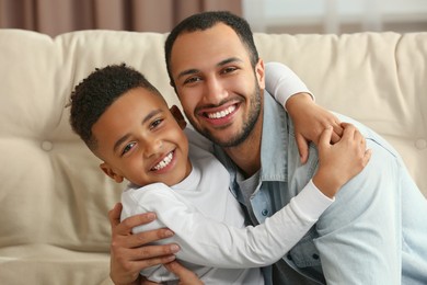 Photo of Father with his African American son on sofa. International family