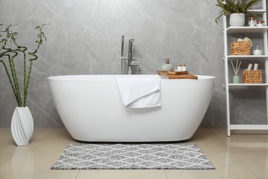 Photo of Soft bath towel and personal care products on tub tray in bathroom