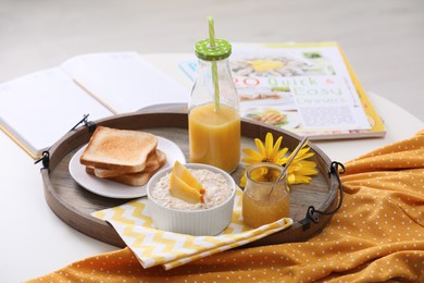 Photo of Wooden tray with delicious breakfast and beautiful flowers on white table indoors