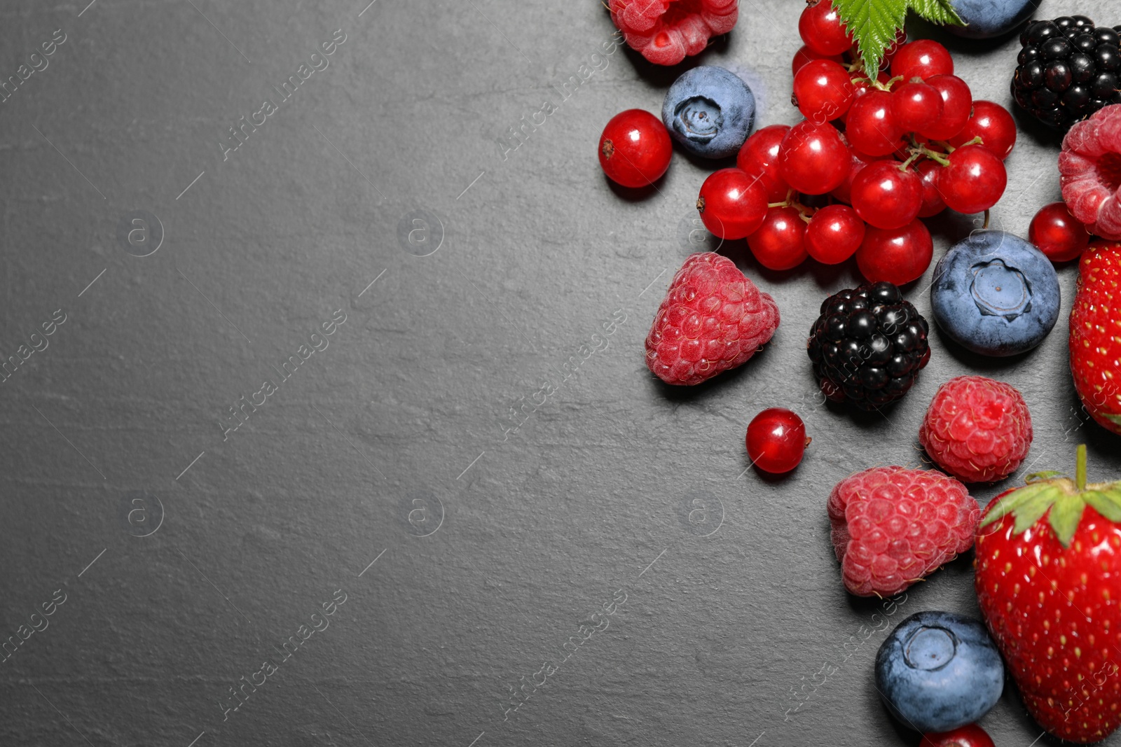 Photo of Different fresh berries on grey background, flat lay. Space for text