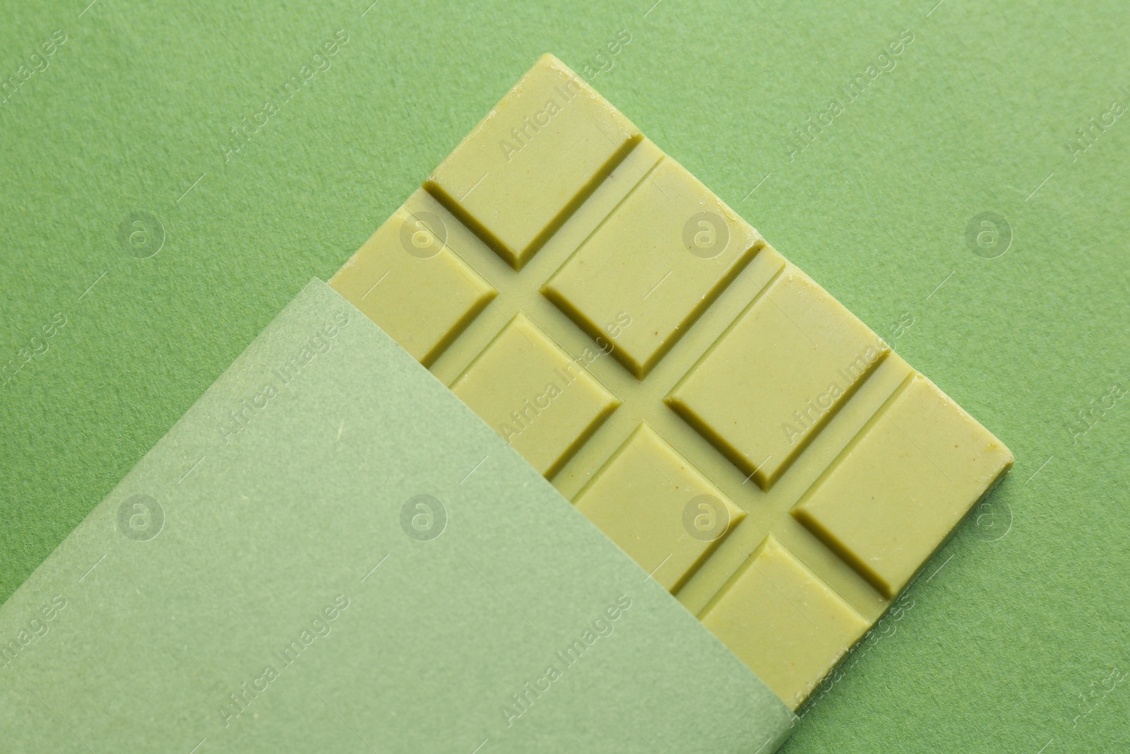 Photo of Tasty matcha chocolate bar on green background, top view