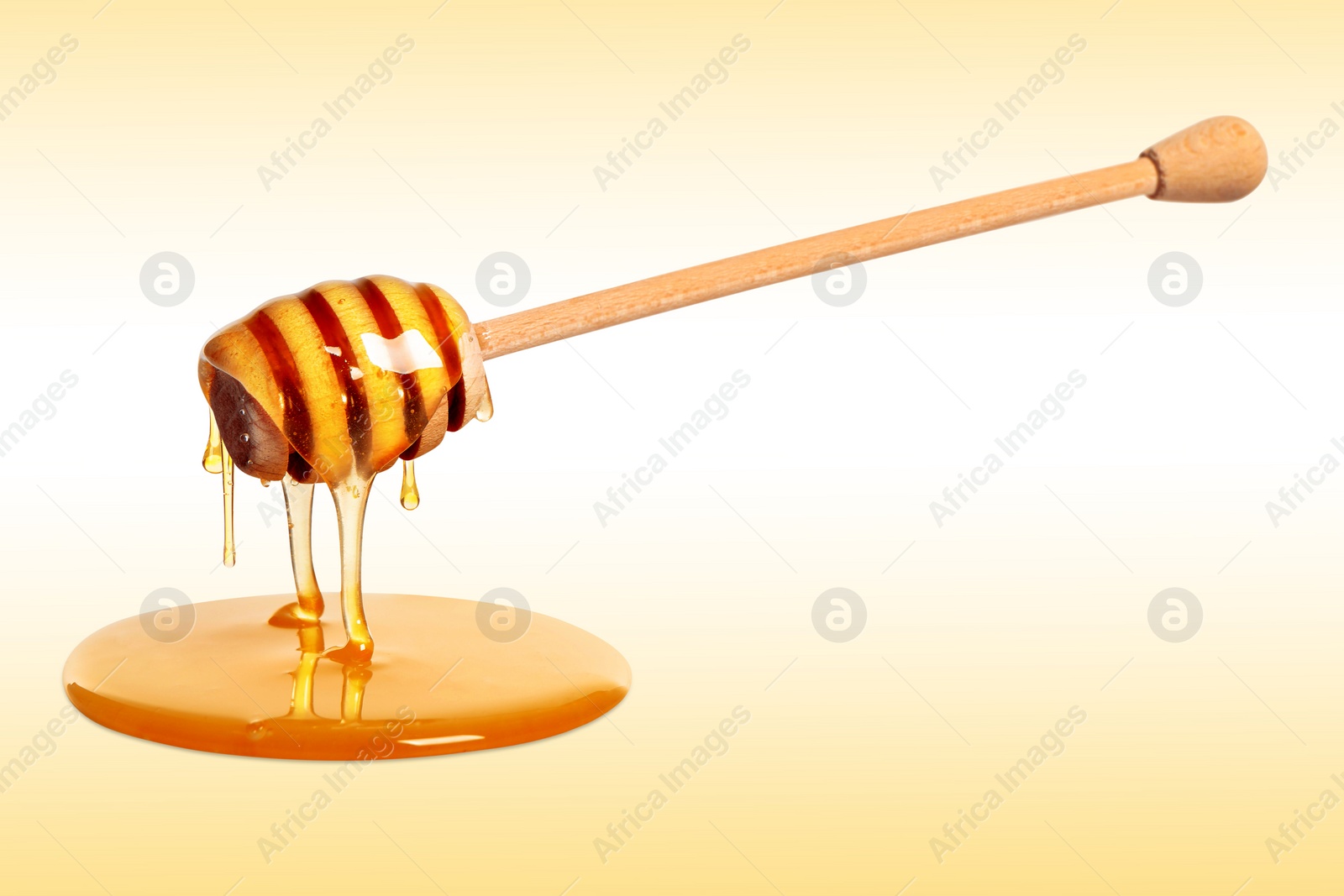 Image of Natural honey dripping from dipper on pale yellow background