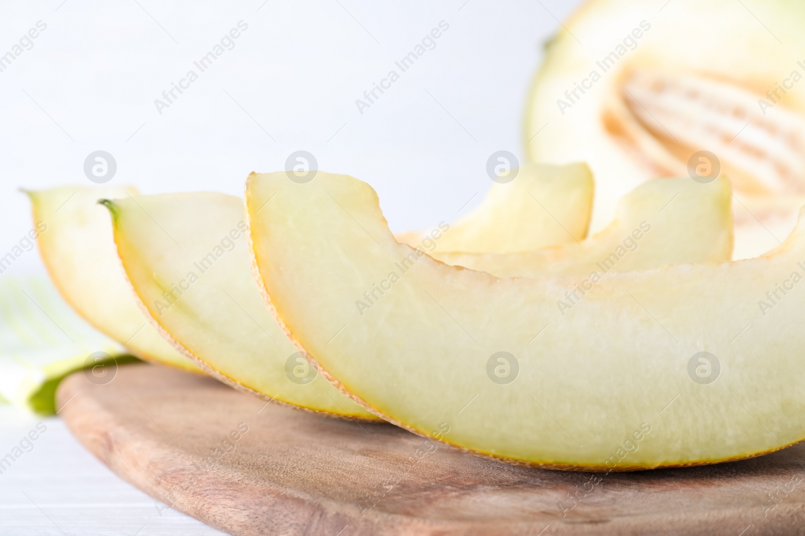 Photo of Pieces of delicious honeydew melon on wooden board, closeup