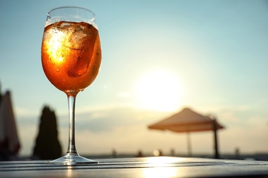 Photo of Glass of fresh summer cocktail on wooden table outdoors at sunset, low angle view. Space for text