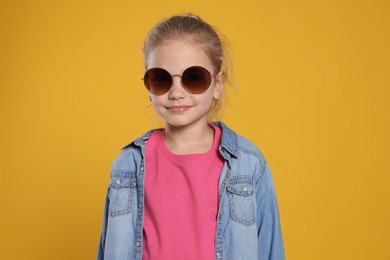 Photo of Girl in stylish sunglasses on orange background