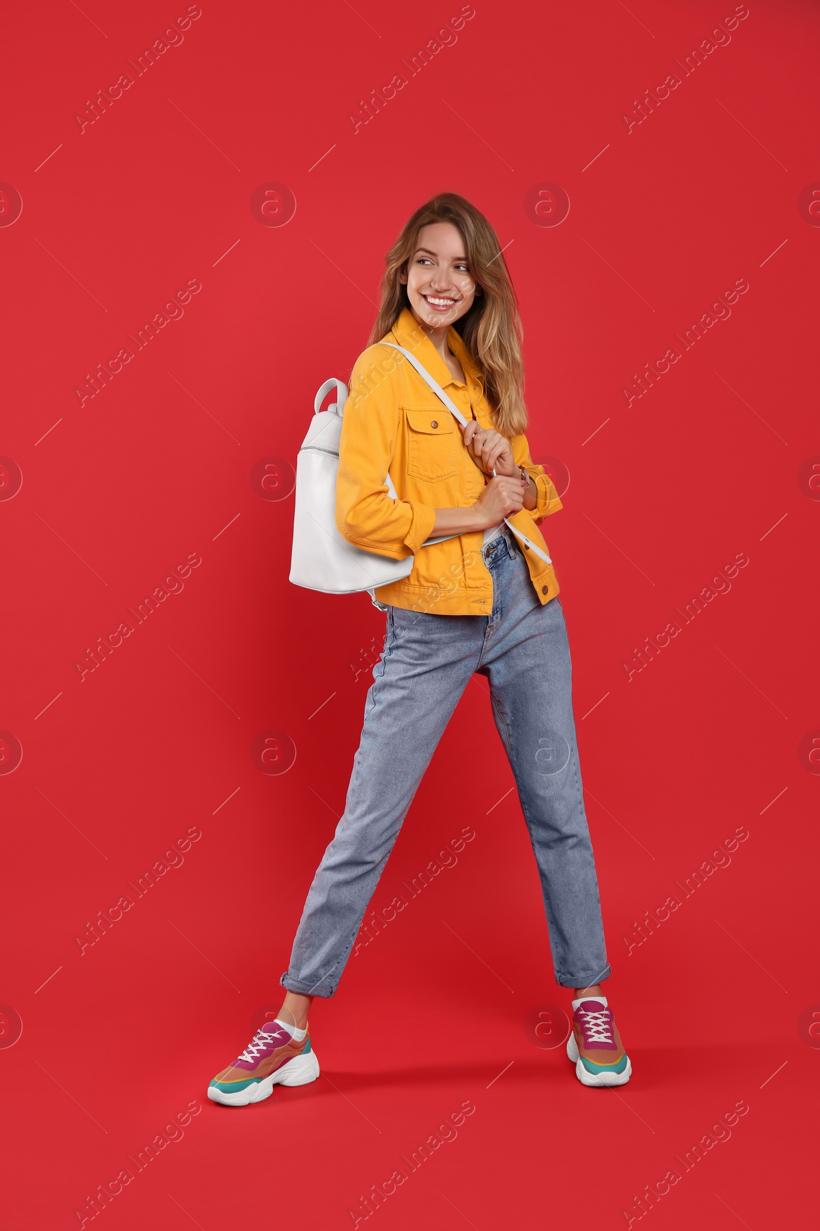 Photo of Happy woman with backpack on red background