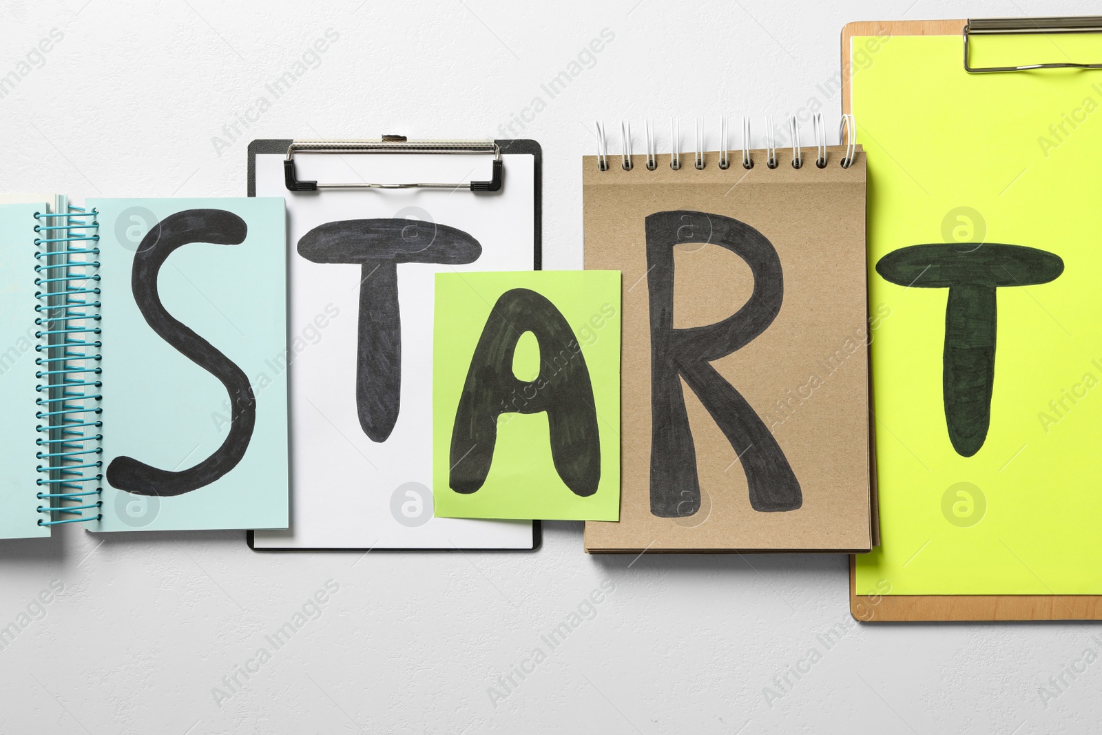 Photo of Notebooks, paper and clipboards with word Start on white background, flat lay