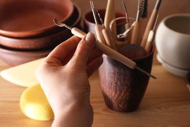 Photo of Woman with clay crafting tool in workshop, closeup