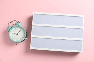 Photo of Blank letter board and alarm clock on pink background, flat lay