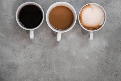 Photo of Cups of fresh aromatic coffee on grey background, top view