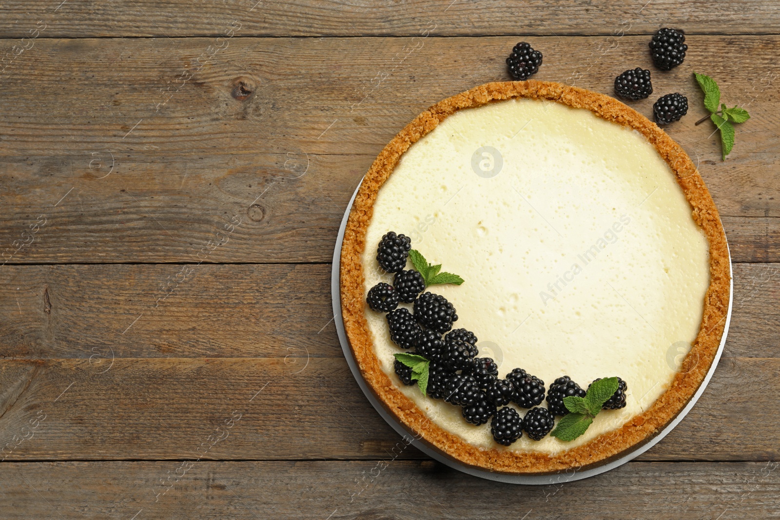 Photo of Delicious cheesecake decorated with blackberries on wooden table, flat lay. Space for text