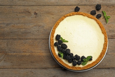 Photo of Delicious cheesecake decorated with blackberries on wooden table, flat lay. Space for text