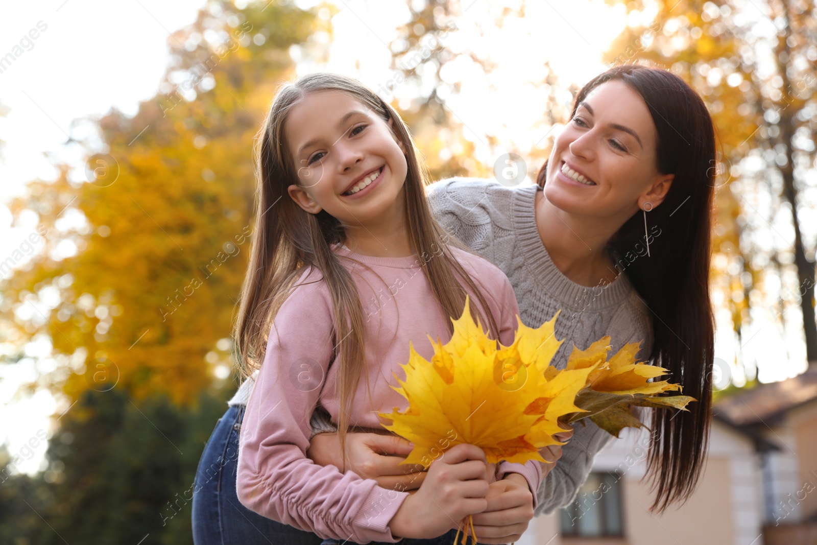 Photo of Happy mother and daughter with yellow leaves in park. Autumn walk