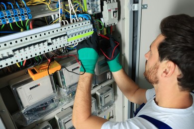 Photo of Electrician checking electric current with multimeter indoors, closeup