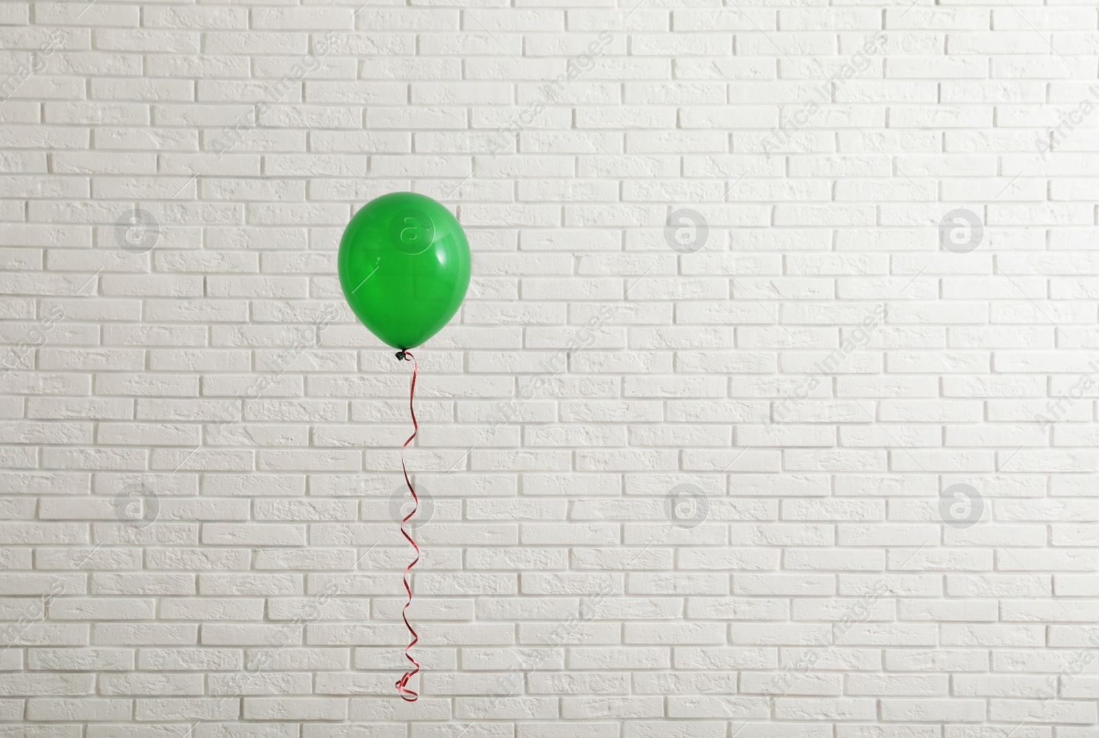 Photo of Bright balloon near brick wall, space for text. Celebration time