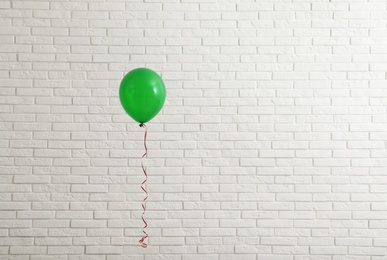 Bright balloon near brick wall, space for text. Celebration time