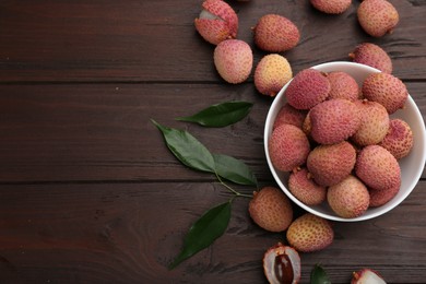 Fresh ripe lychee fruits on wooden table, flat lay. Space for text