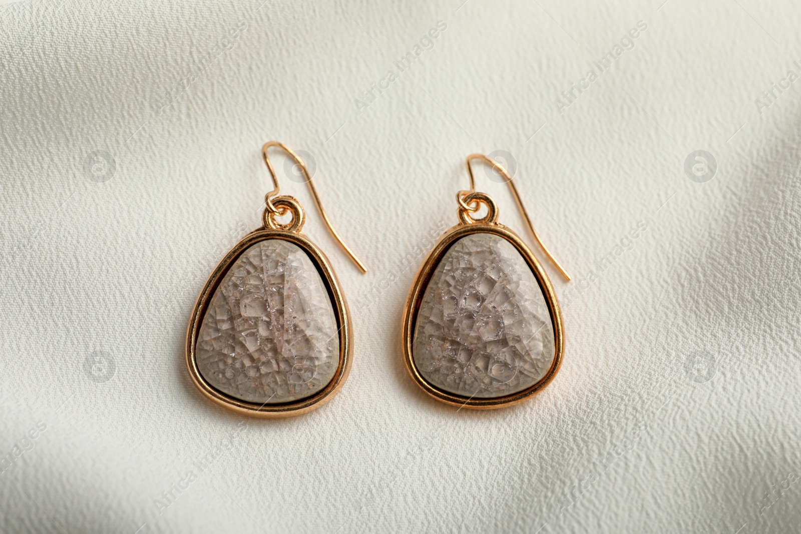 Photo of Elegant earrings on white fabric, flat lay. Stylish bijouterie