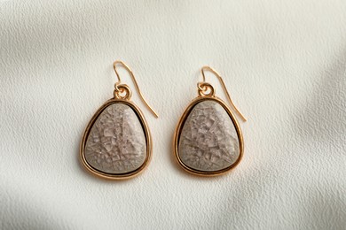 Photo of Elegant earrings on white fabric, flat lay. Stylish bijouterie