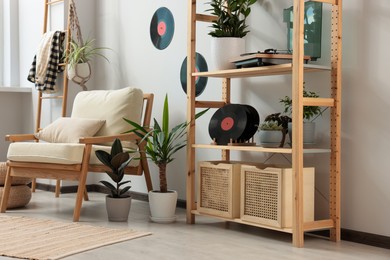 Photo of Living room interior with stylish turntable on wooden shelving unit and vinyl records