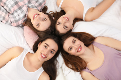 Photo of Beautiful young ladies on bed at pamper party, above view. Woman's Day