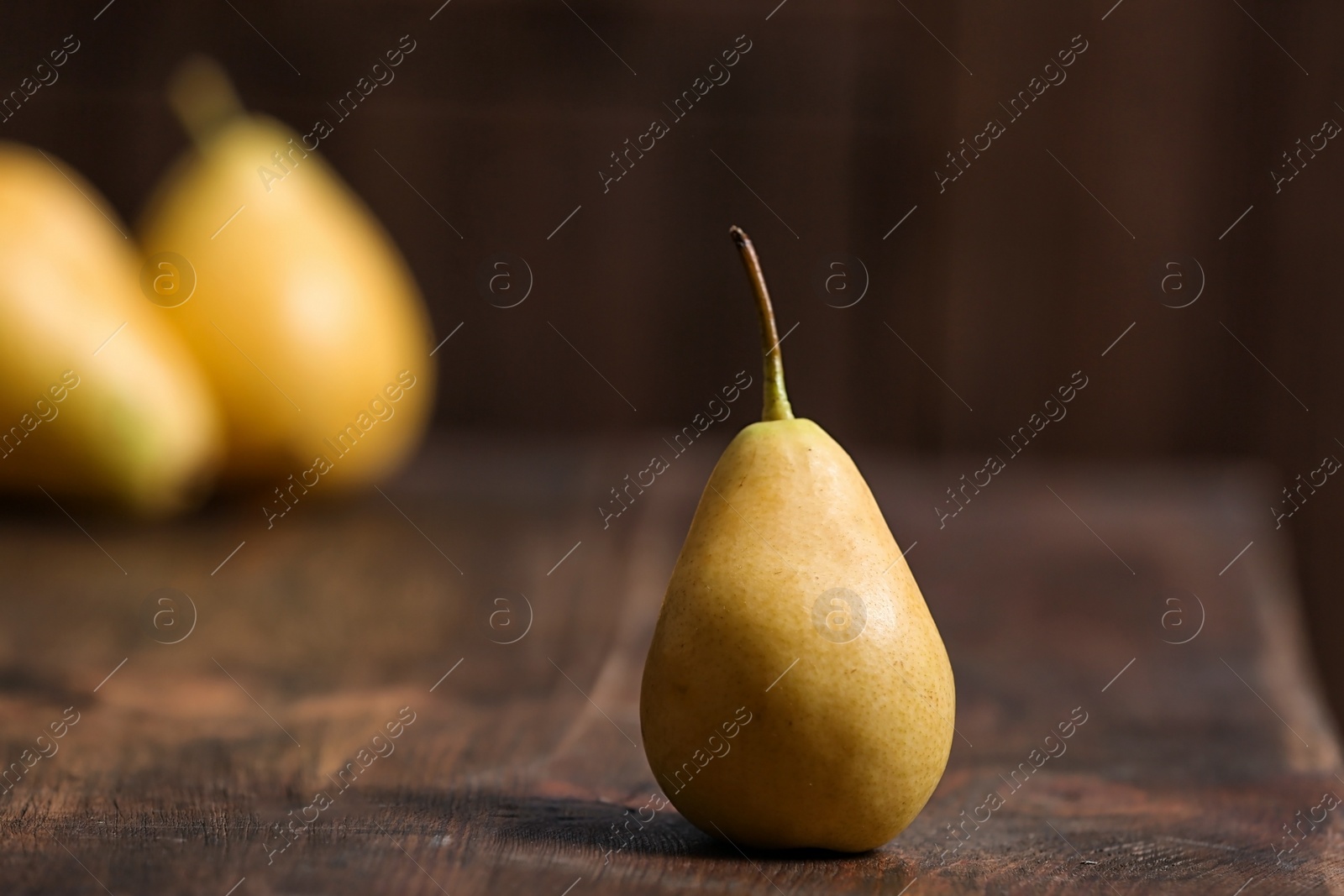 Photo of Tasty ripe yellow pear on wooden table