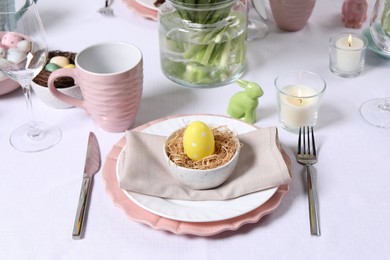 Photo of Festive table setting with painted egg in decorative nest. Easter celebration