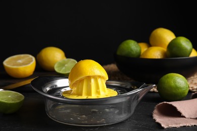 Squeezer, fresh lemons and limes on black table