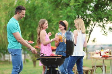 Photo of Young people having barbecue with modern grill outdoors