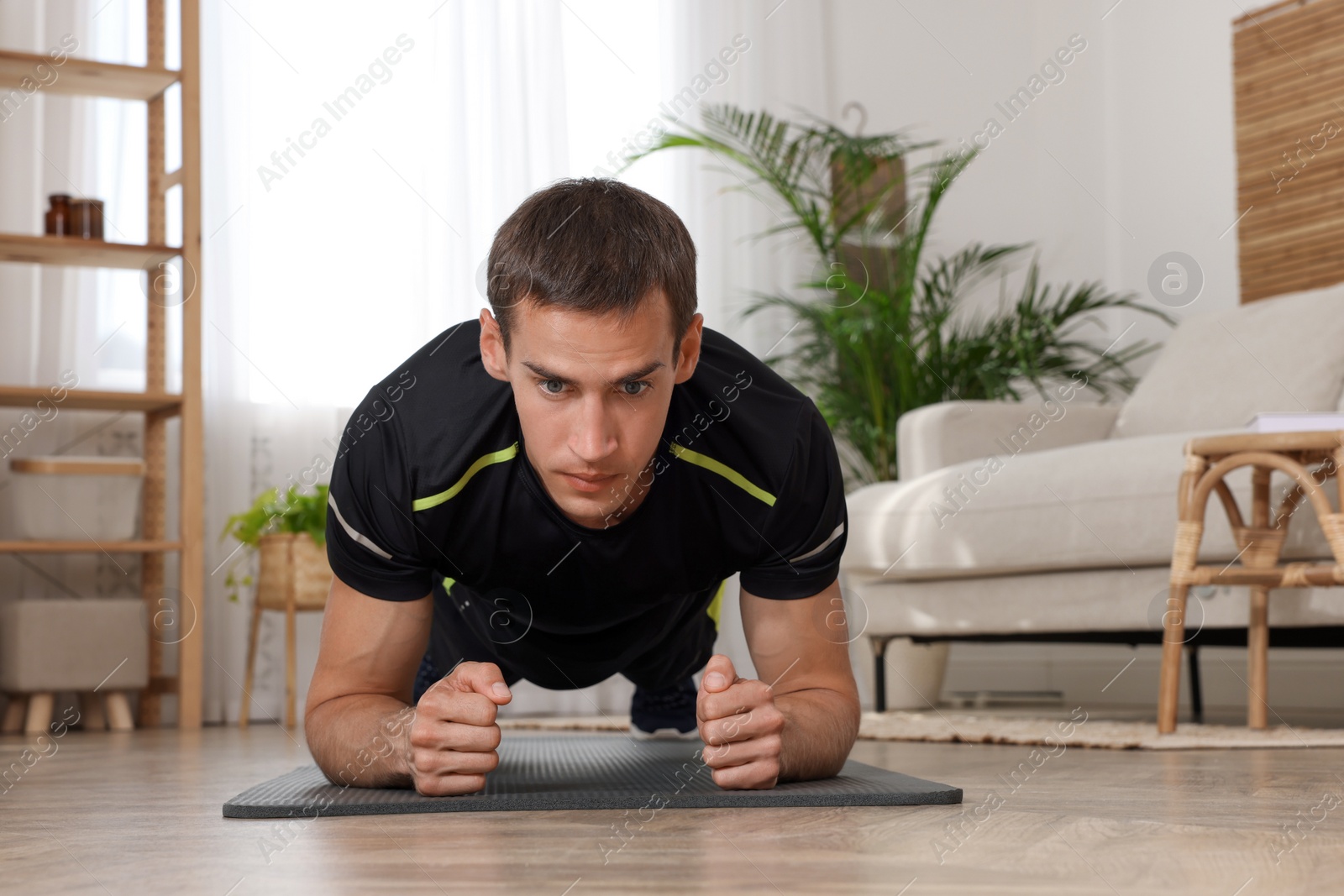 Photo of Handsome man doing plank exercise on floor at home