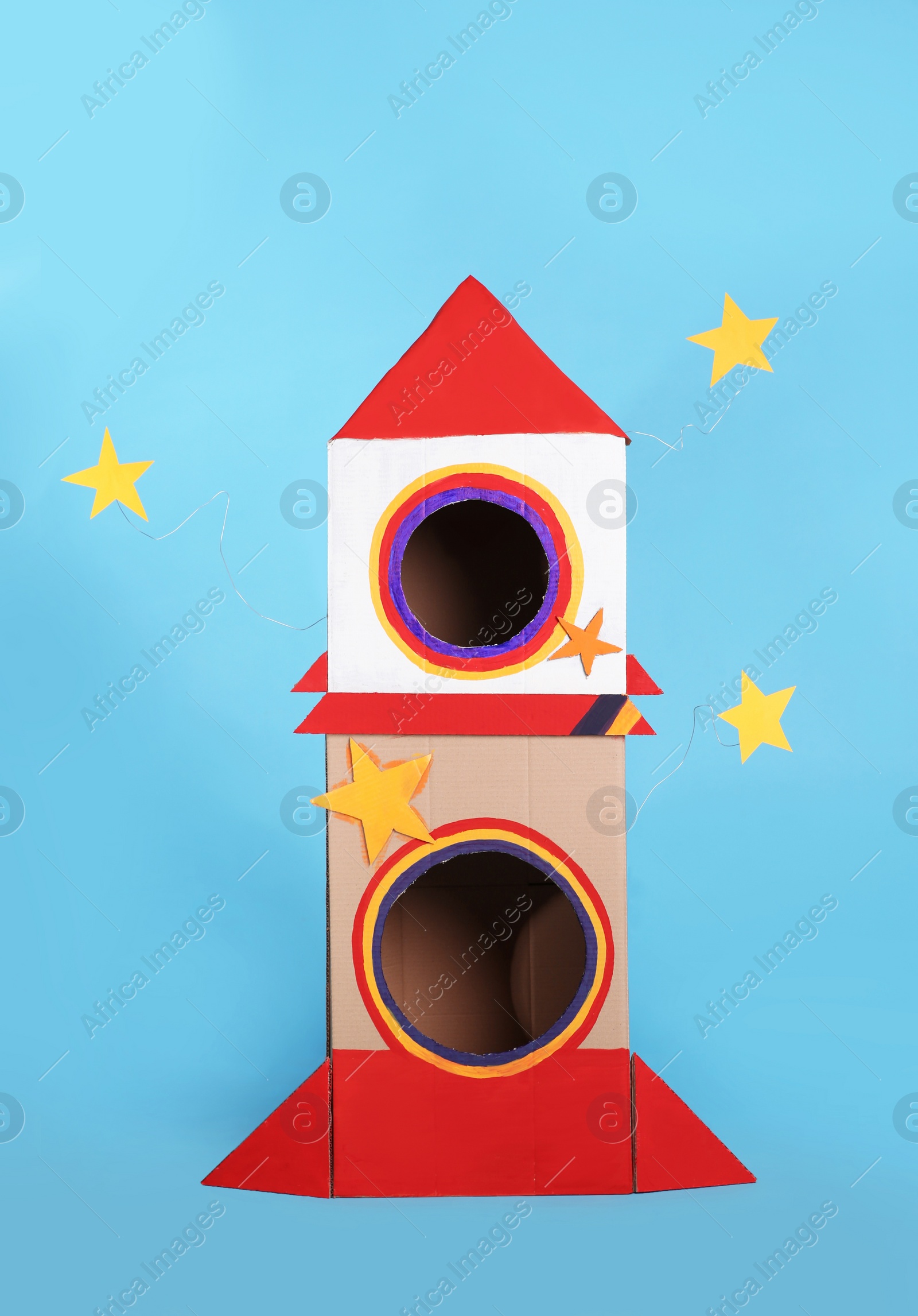 Photo of Cute handmade cardboard spaceship on light blue background