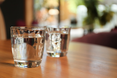 Glasses of water on wooden table in cafe. Space for text