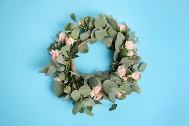 Wreath made of beautiful flowers on light blue background, top view