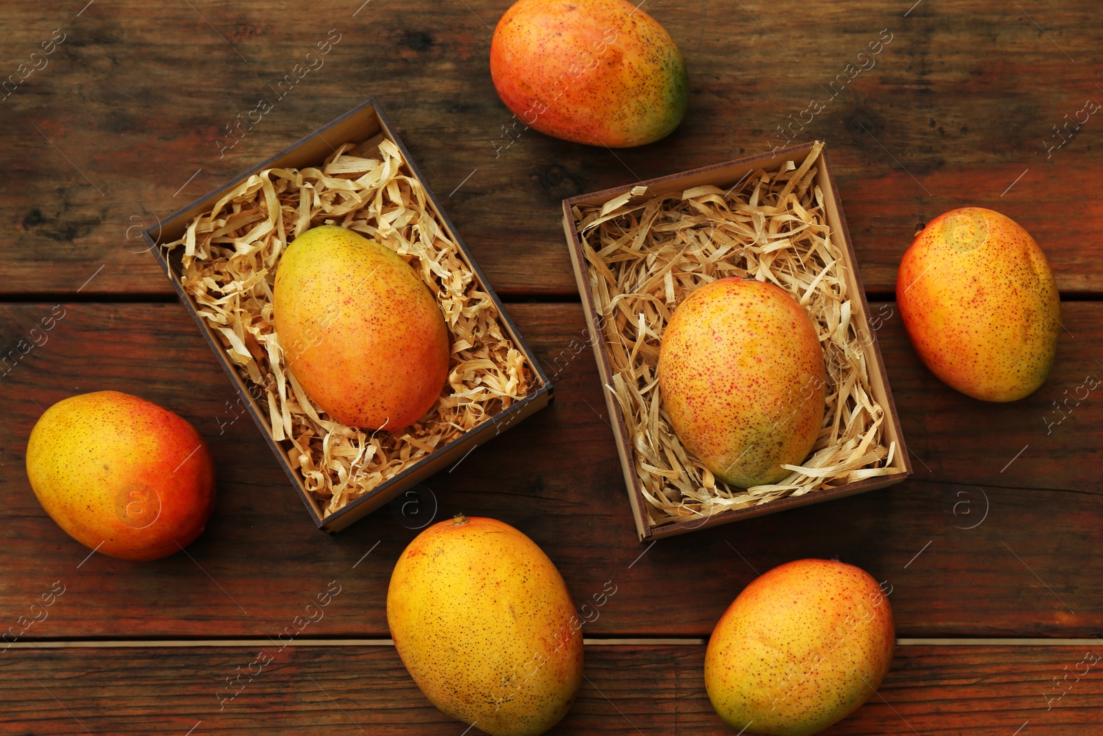 Photo of Delicious ripe juicy mangos on wooden table, flat lay