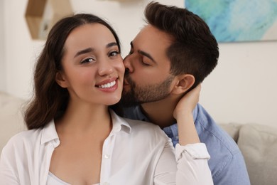 Photo of Young man kissing his girlfriend at home