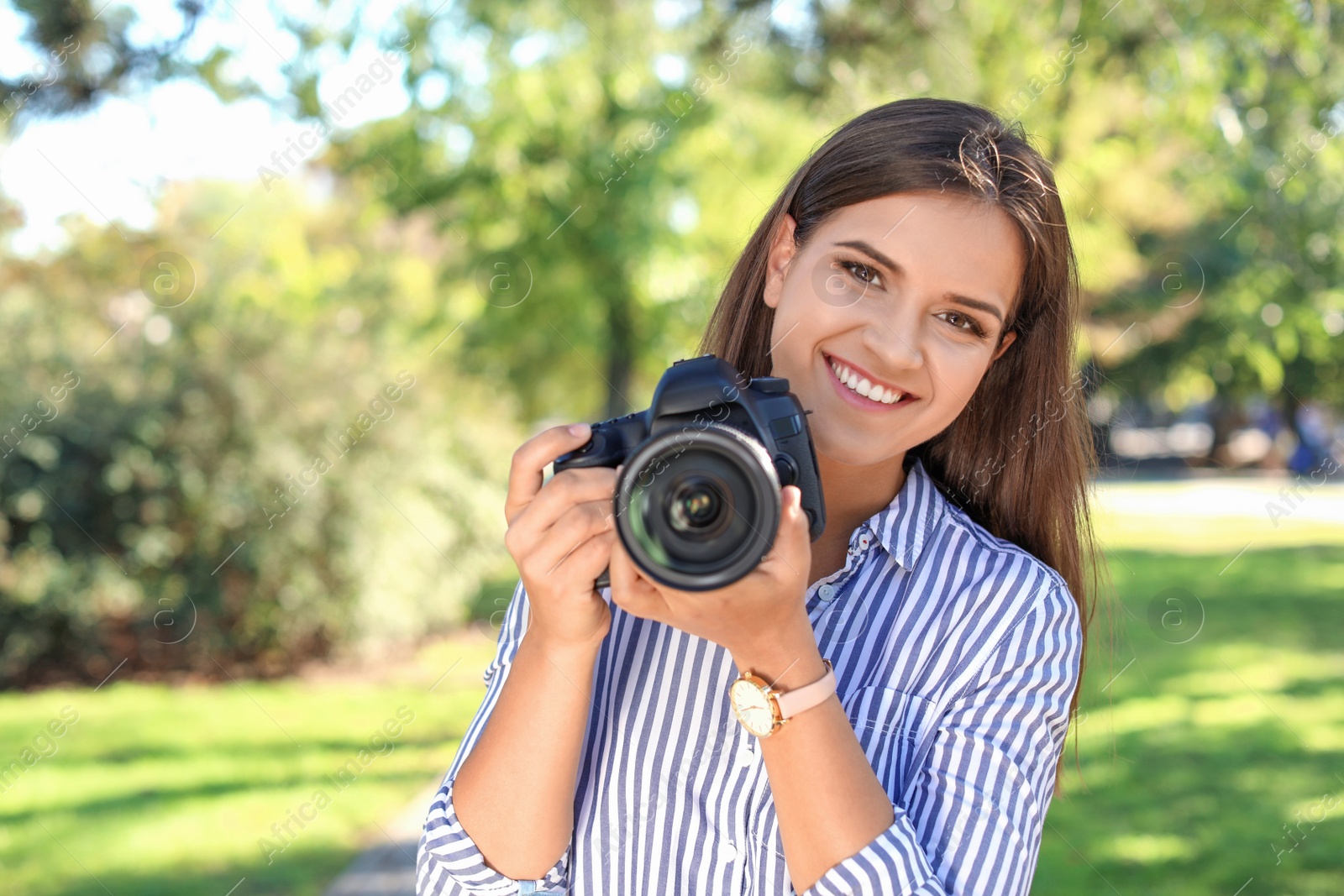 Photo of Young female photographer with professional camera in park